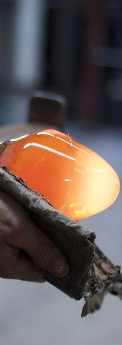 Hot Gather of Molten Glass Hand holding a glowing orange glass object, showcasing its translucent quality.