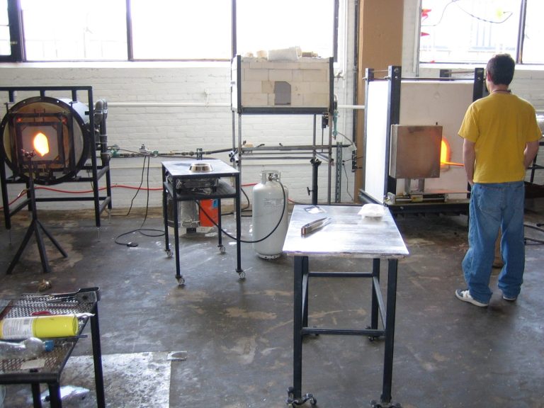 Garrett Wheeler Glass Blowing Glass A glassblowing studio with work tables, equipment, and a furnace.